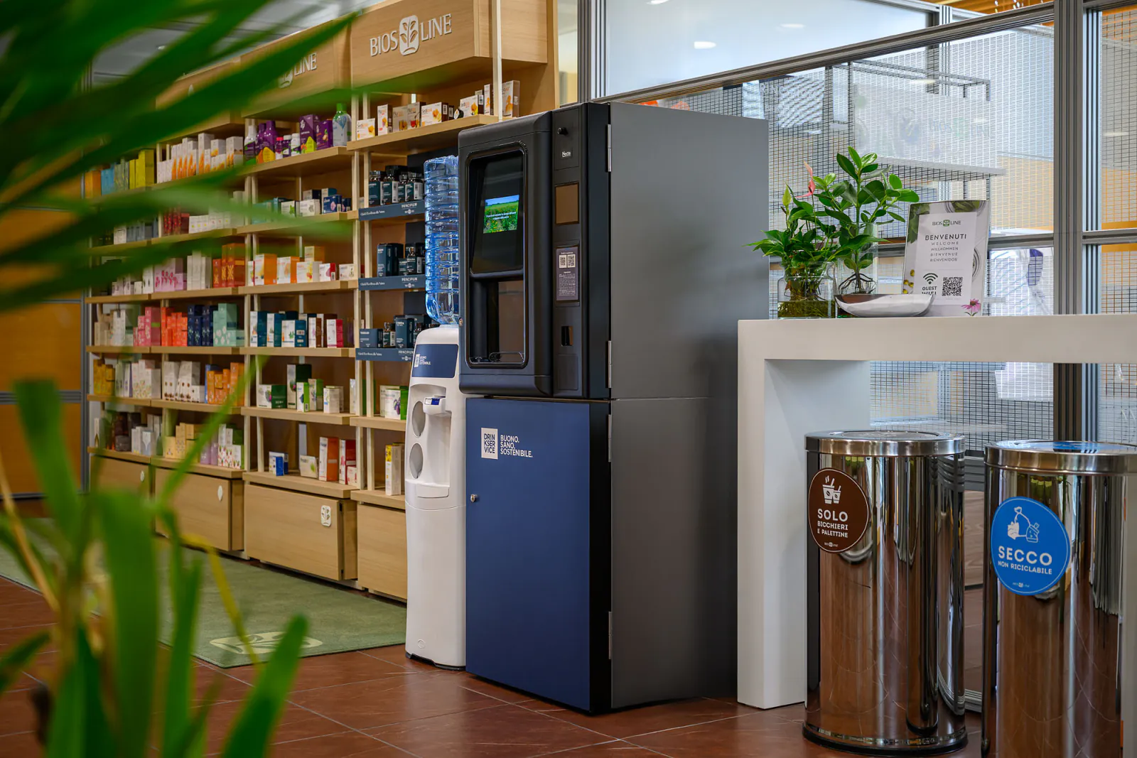 Postazione DrinkService nel punto vendita, con scaffali in legno e dispenser a boccione.