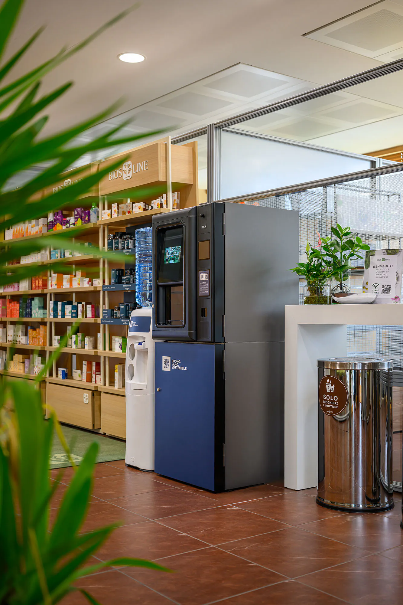 Postazione DrinkService nel punto vendita, con scaffali in legno e dispenser a boccione.