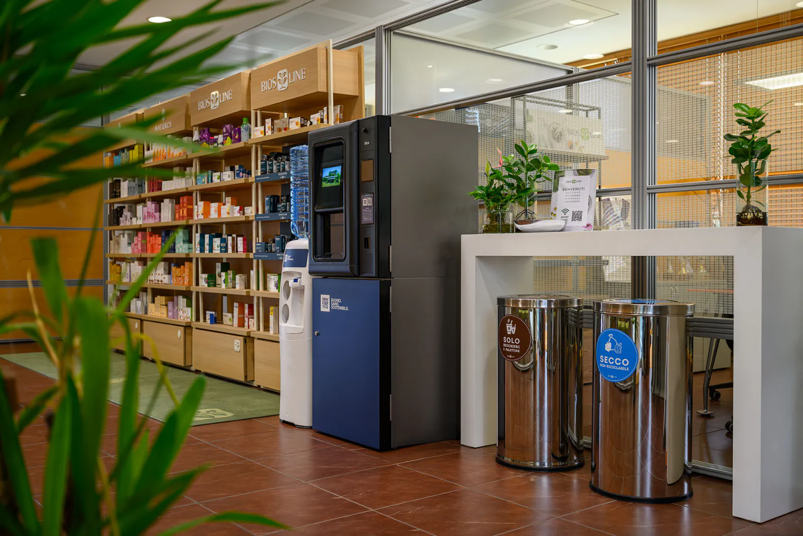 Postazione DrinkService nel punto vendita, con scaffali in legno e dispenser a boccione.