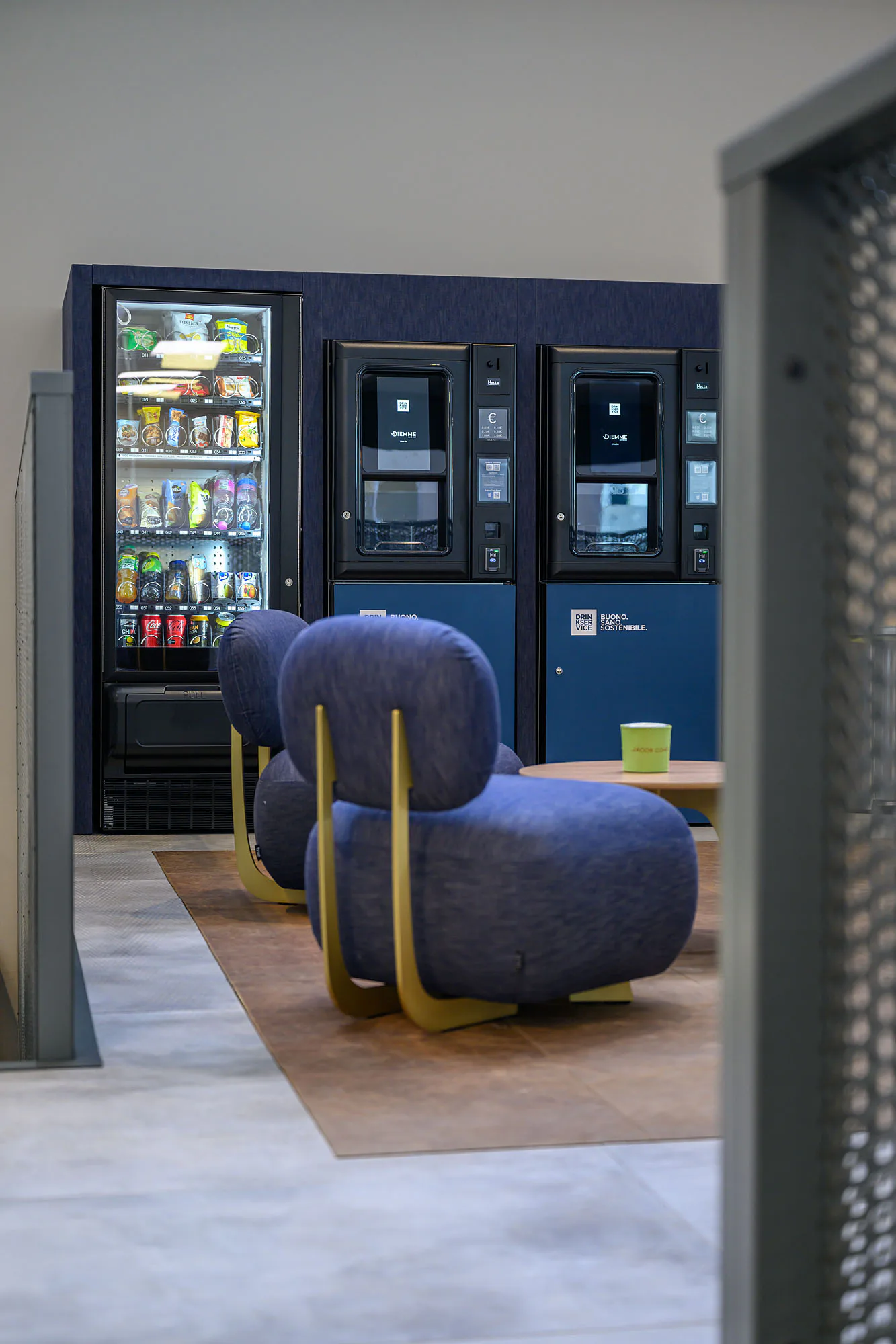 I distributori inquadrati dal vano di una porta, con il tappeto e le sedute in denim nel mezzo.