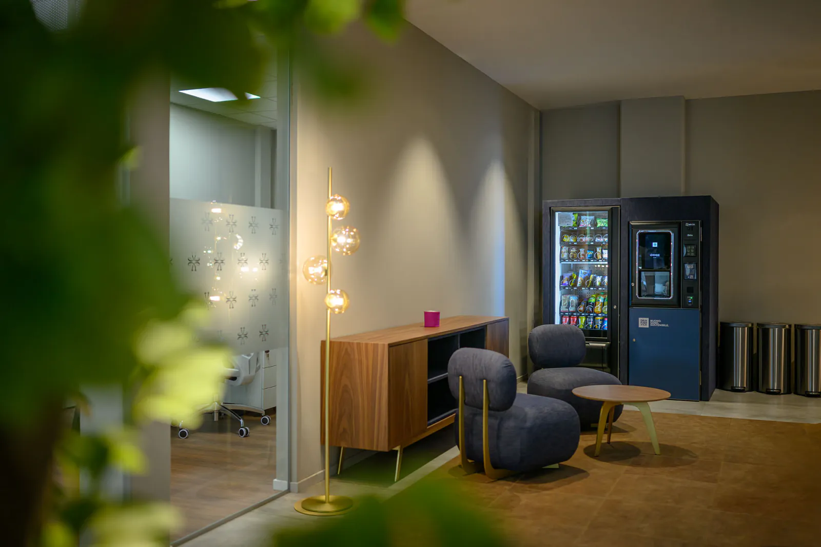 Area break con distributori rivestiti in denim blu, sedute coordinate e illuminazione decorativa.