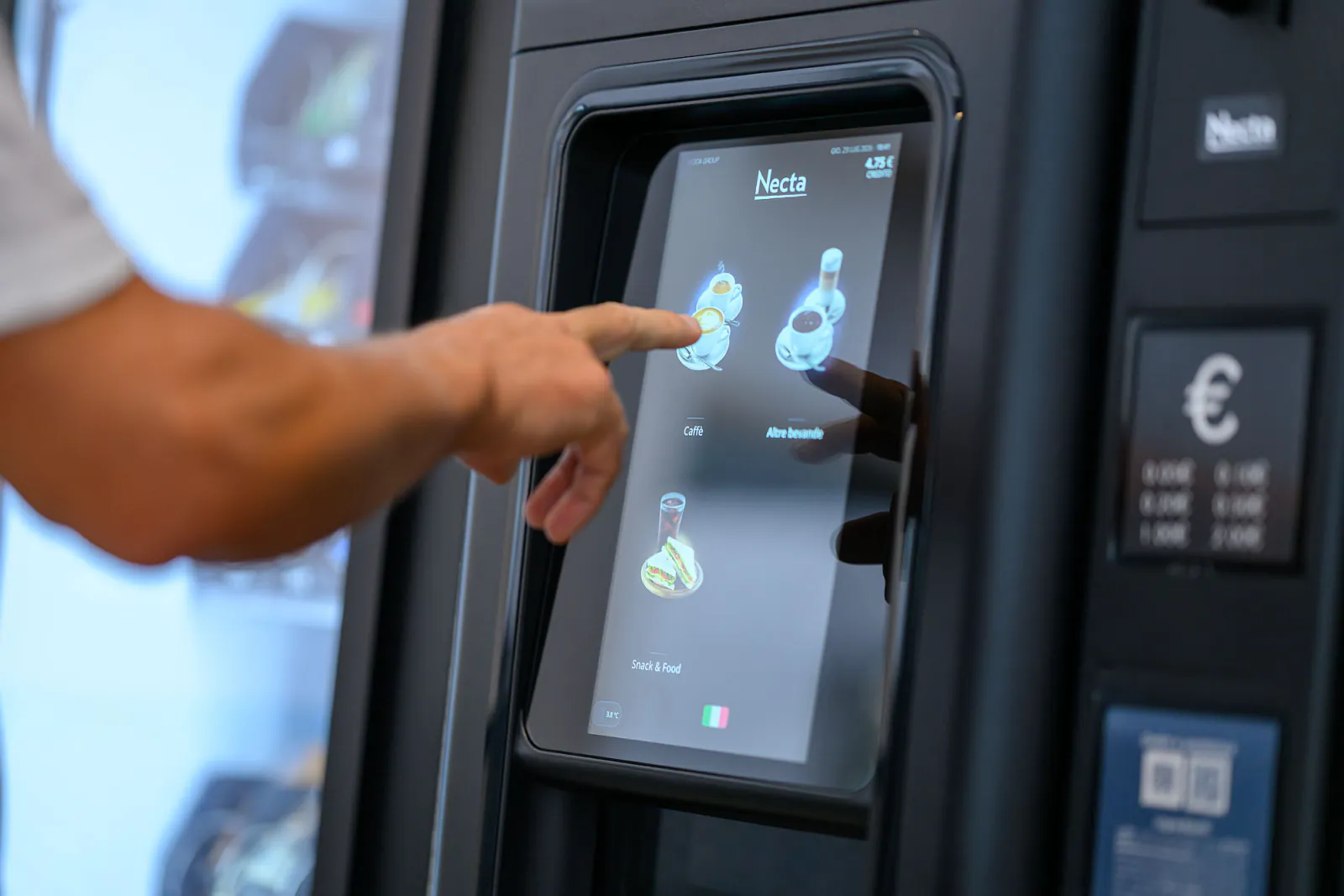 Una persona utilizza il distributore, con le altre macchine dell’installazione visibili accanto.