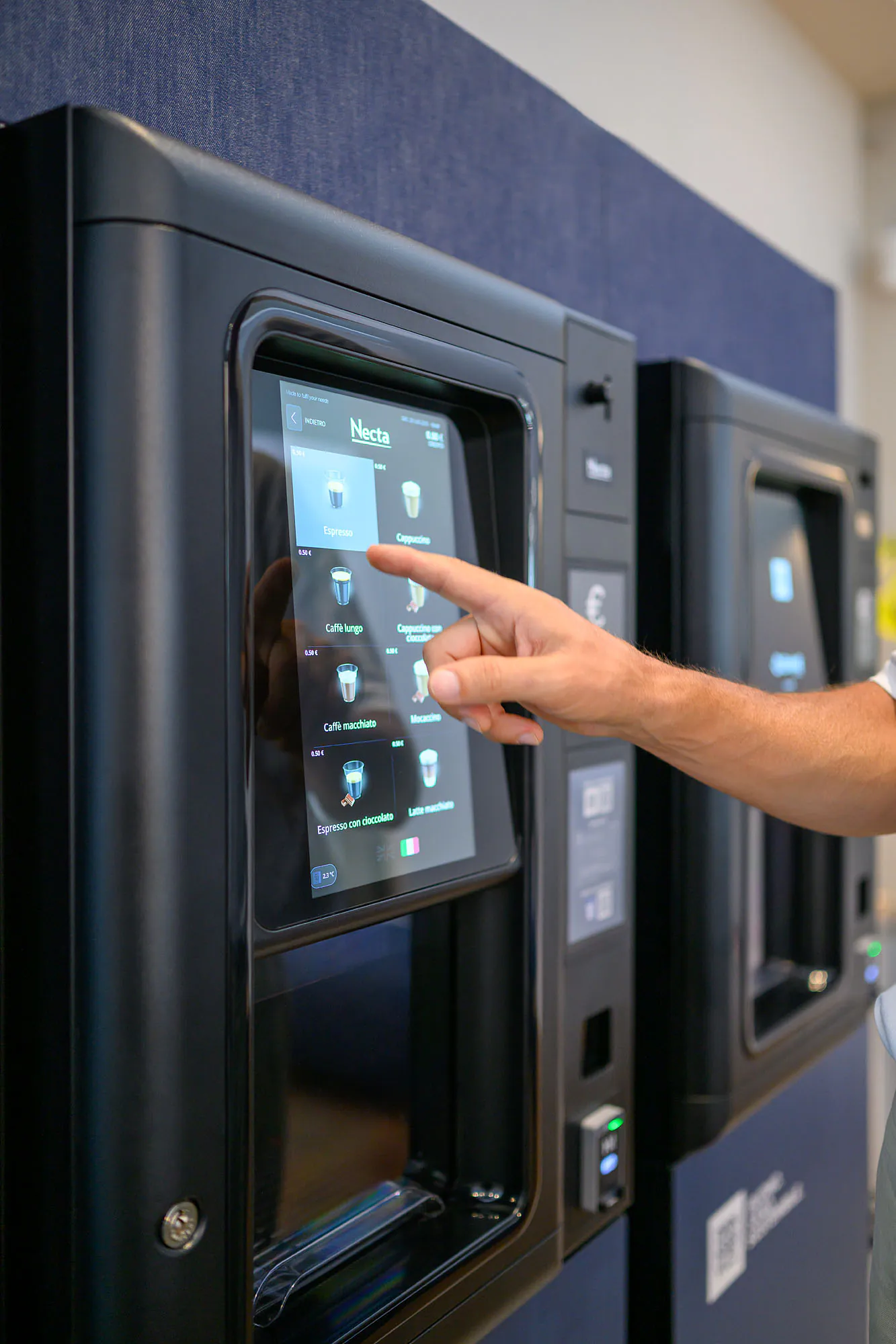 Una persona utilizza il distributore, con le altre macchine dell’installazione visibili accanto.