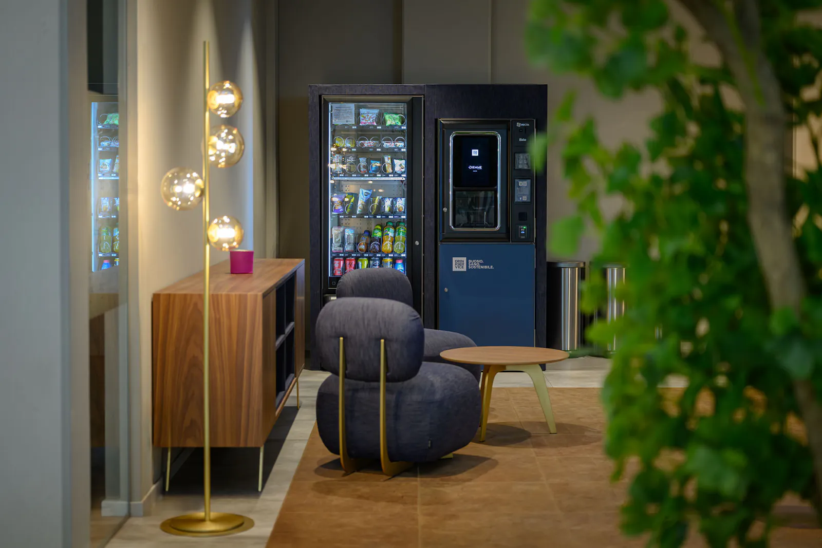 Area break con distributori rivestiti in denim blu, sedute coordinate e illuminazione decorativa.