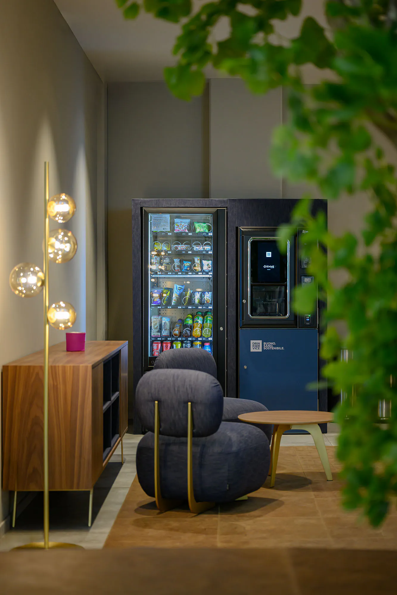 Area break con distributori rivestiti in denim blu, sedute coordinate e illuminazione decorativa.