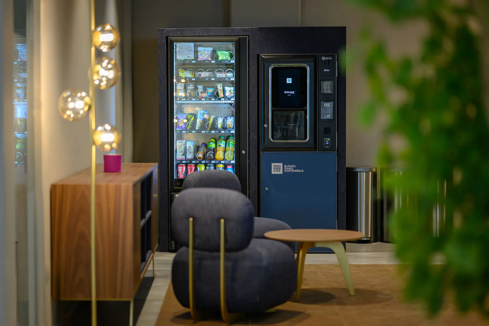 Area break con distributori rivestiti in denim blu, sedute coordinate e illuminazione decorativa.