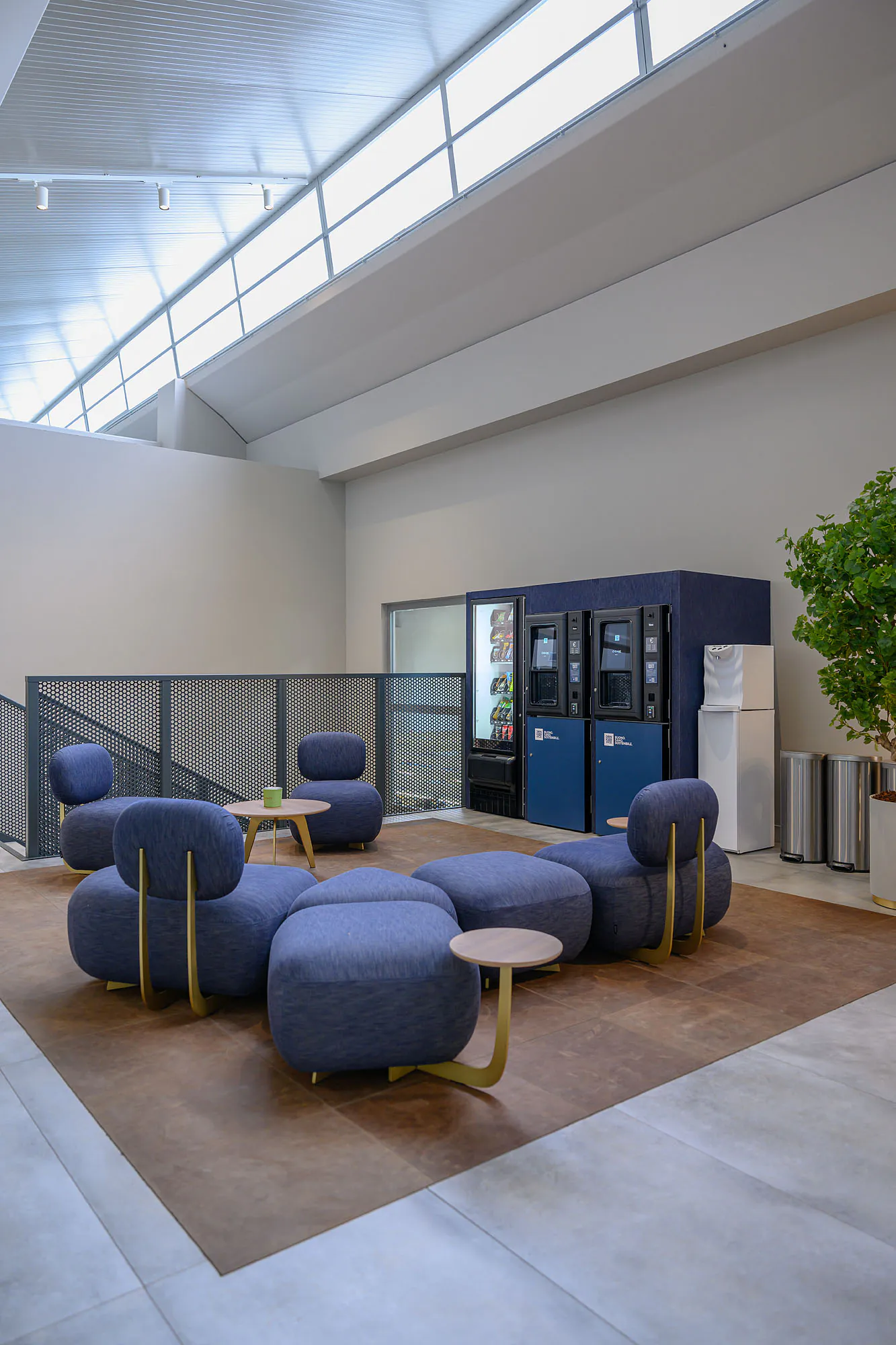 Area break con distributori rivestiti in denim blu, sedute coordinate e illuminazione decorativa.