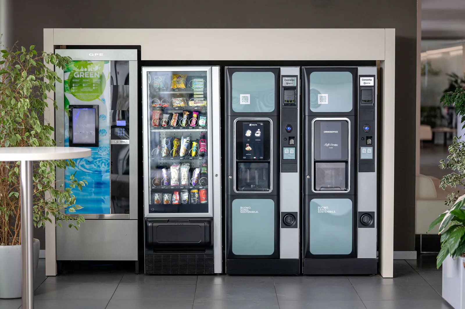 I quattro distributori visti di fronte: erogatore di acqua con schermo verticale, macchina per snack e bevande fredde, due macchine per il caffe'.